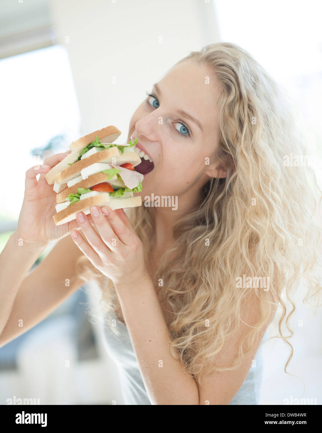 Portrait de impatient woman eating sandwich en grande chambre Banque D'Images