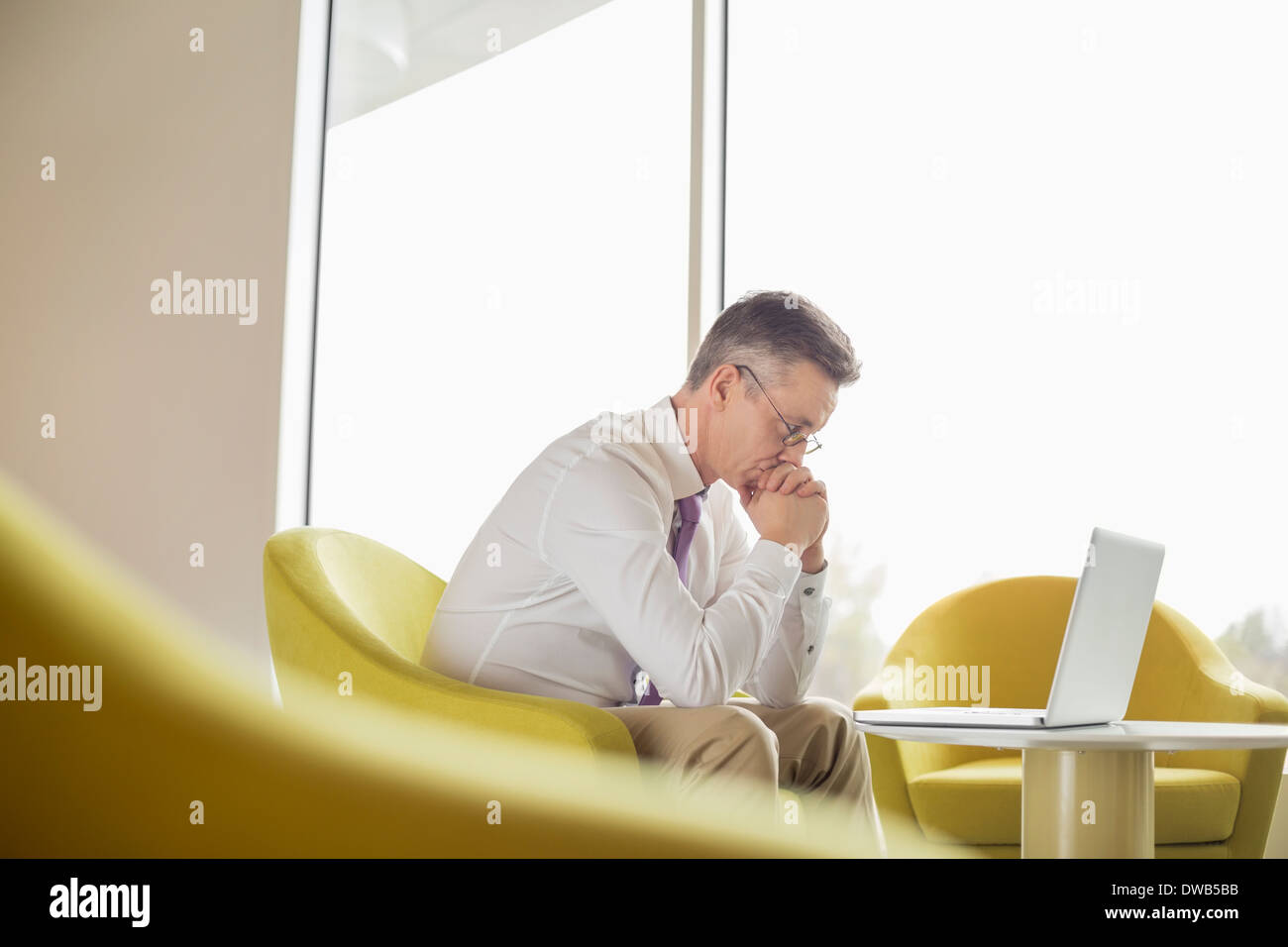 Vue latérale du serious businessman looking at laptop in lobby Banque D'Images