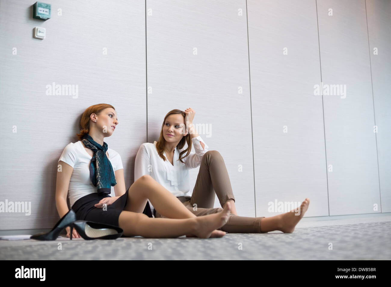 Fatigué businesswomen sitting on floor in office Banque D'Images