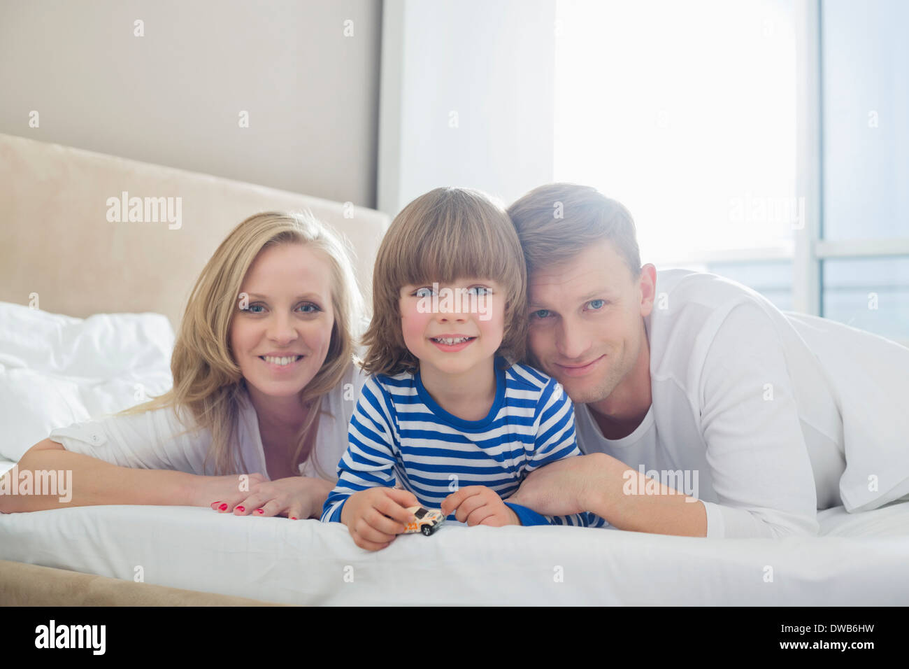 Portrait of happy parents couchant avec fils au lit Banque D'Images