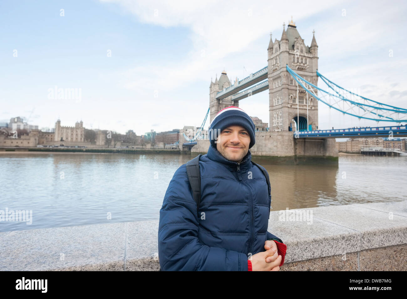 Portrait of mid adult man dans des vêtements chauds debout devant le Tower Bridge, London, UK Banque D'Images