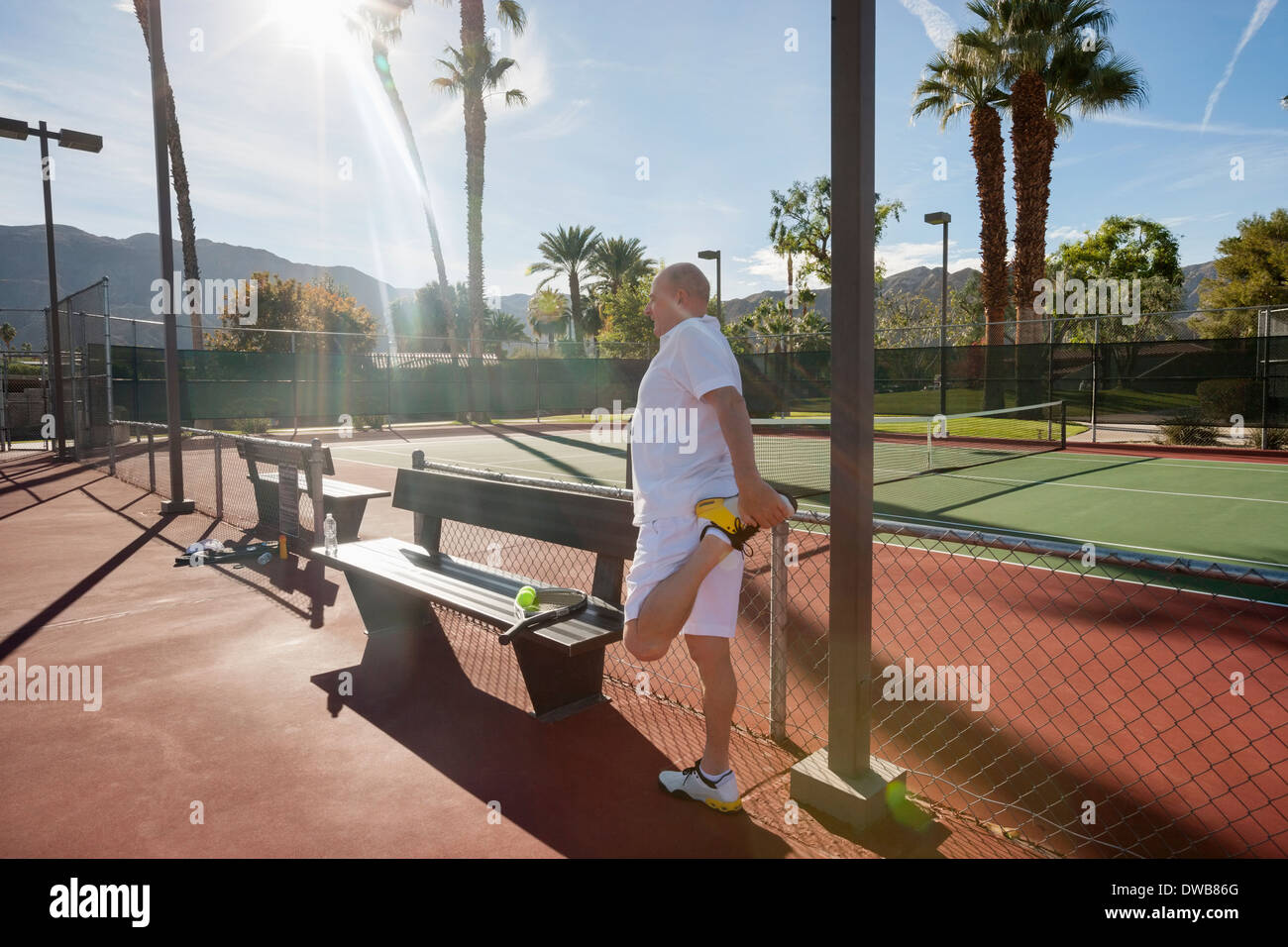 Senior male tennis player s'étendant de la jambe sur cour Banque D'Images