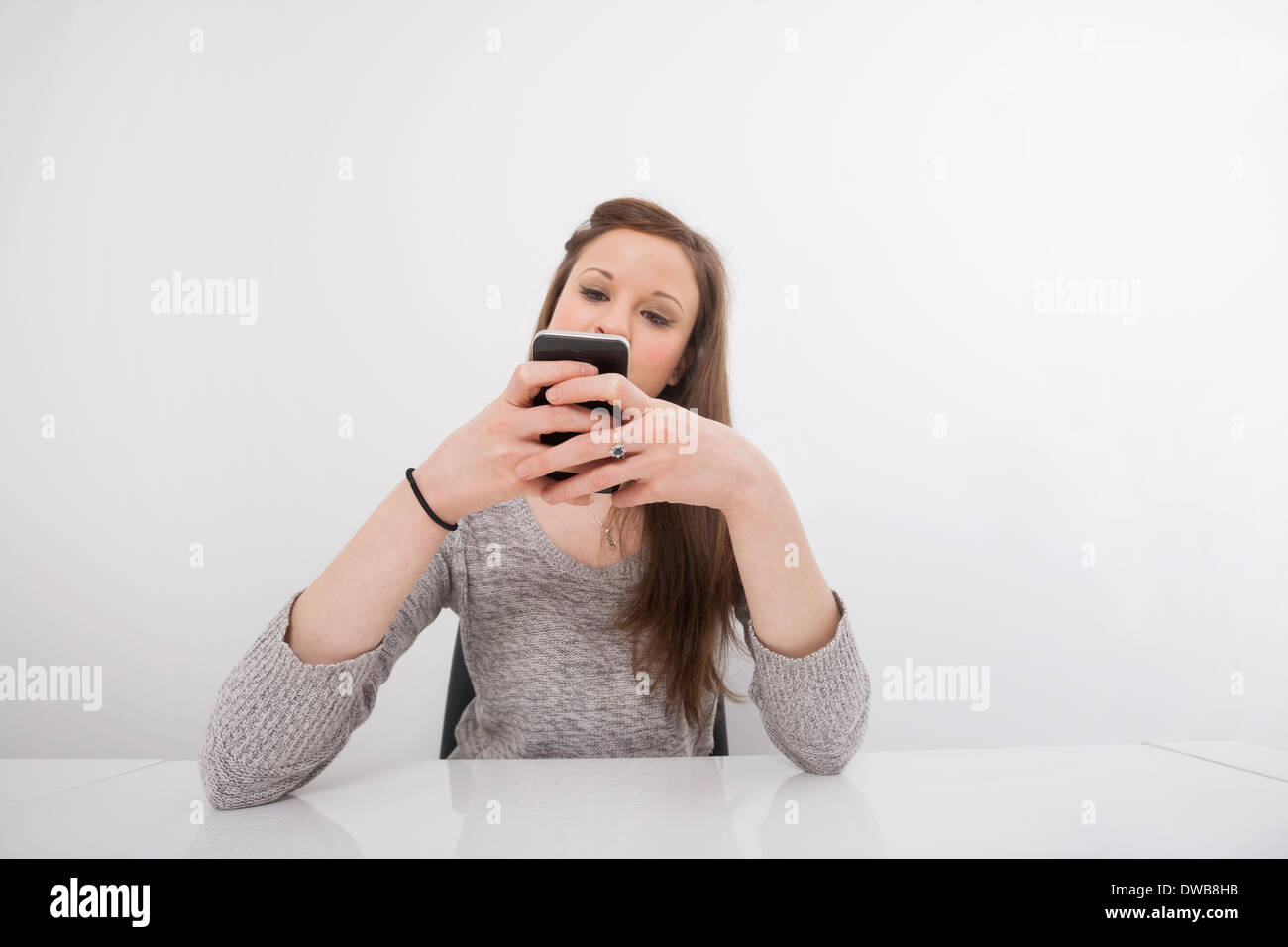 Young businesswoman text messaging on smart phone at office desk Banque D'Images