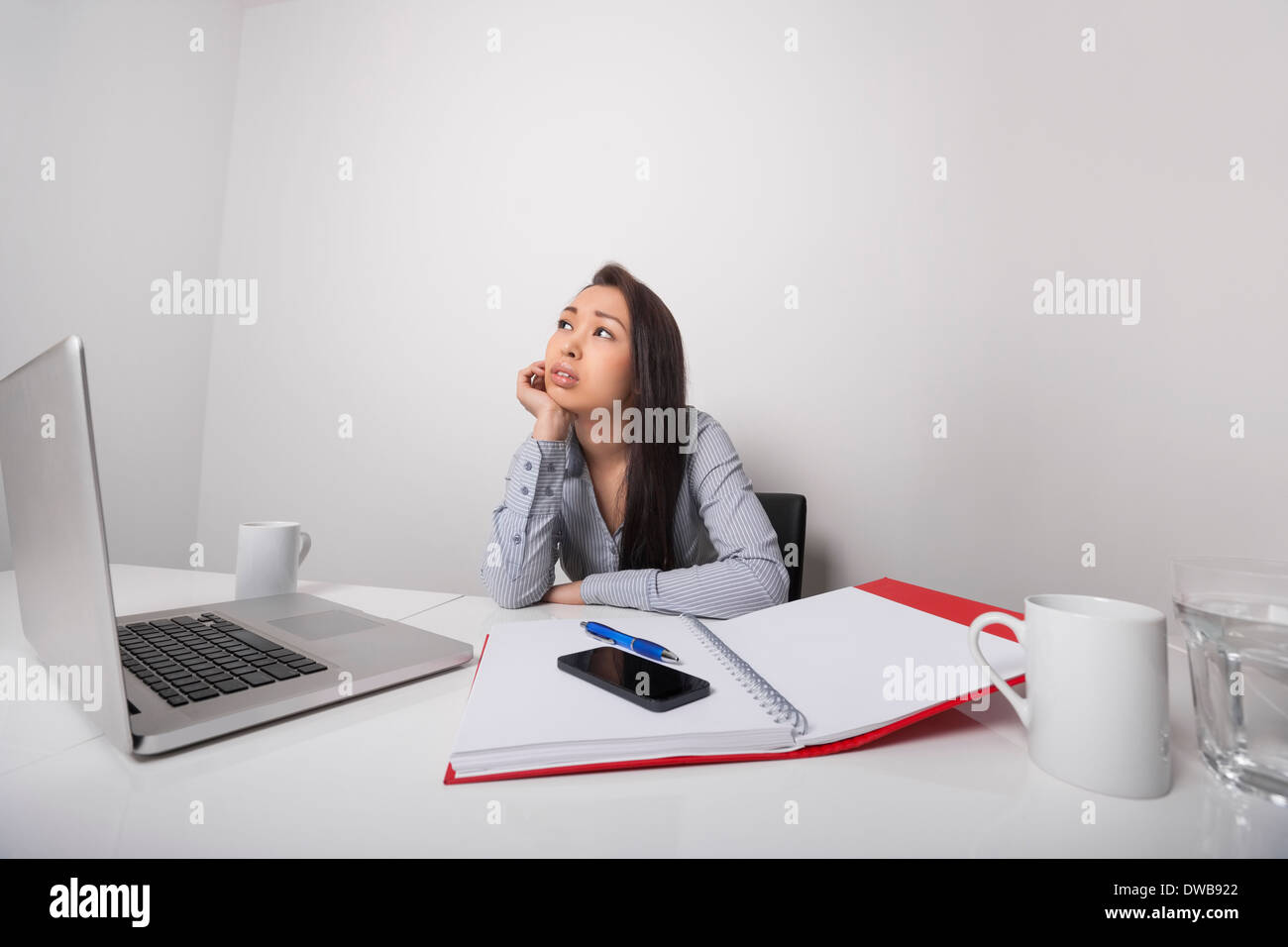 Thoughtful businesswoman sitting at desk in office Banque D'Images