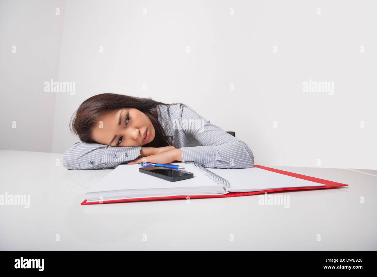 Épuisé woman smiling at office desk Banque D'Images