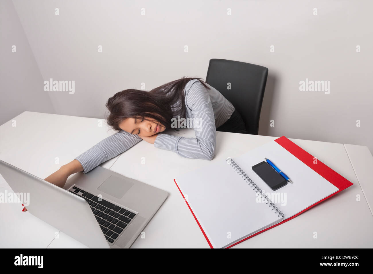 Épuisé businesswoman sleeping at office desk Banque D'Images