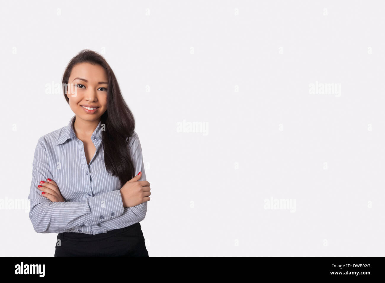 Portrait of businesswoman standing arms crossed contre l'arrière-plan gris Banque D'Images