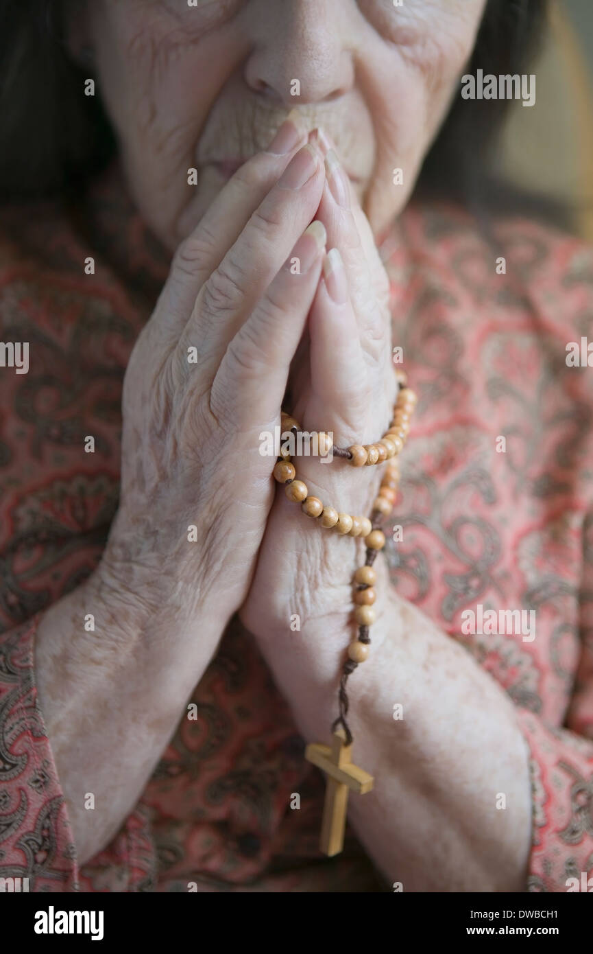 Femme en prière avec le chapelet senior Banque D'Images