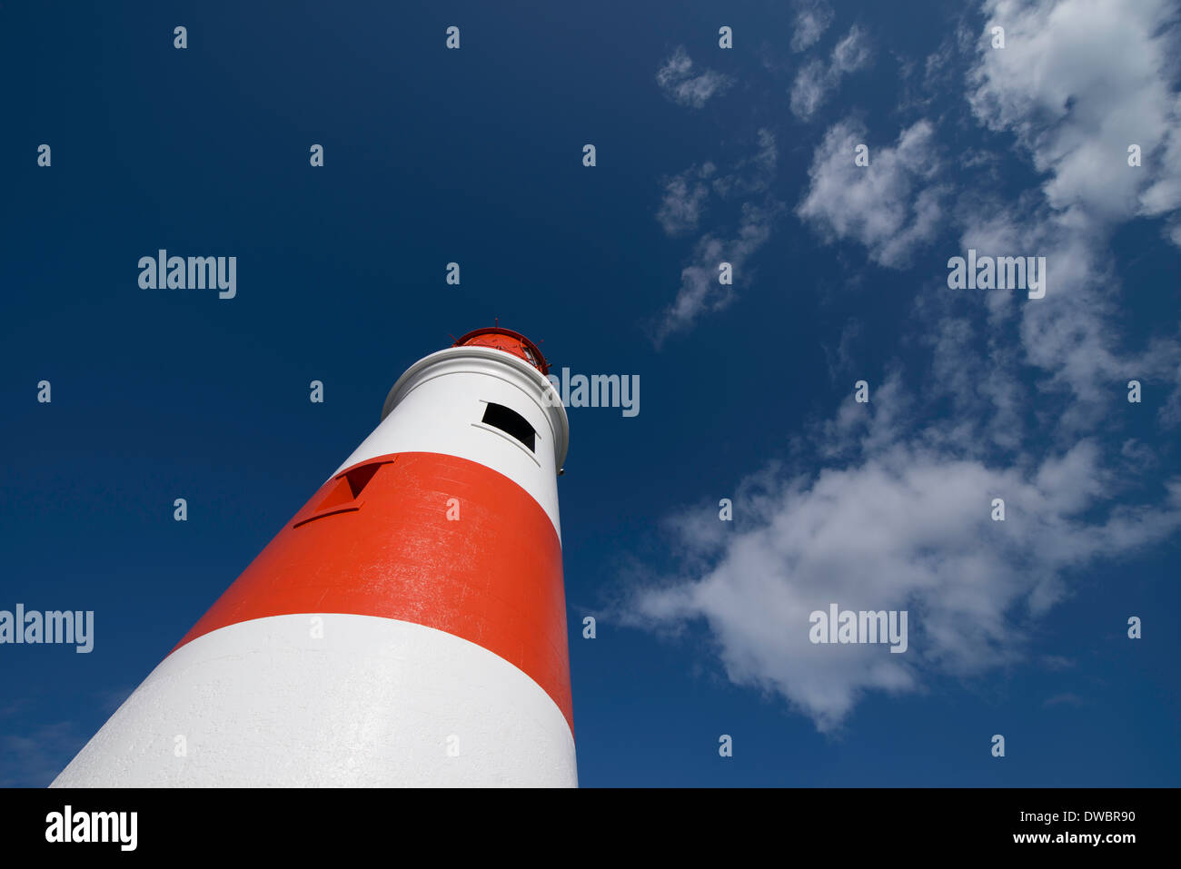 Detail shot de la tour d'un phare rouge et blanc s'étendant jusqu'à un ciel bleu profond. Banque D'Images