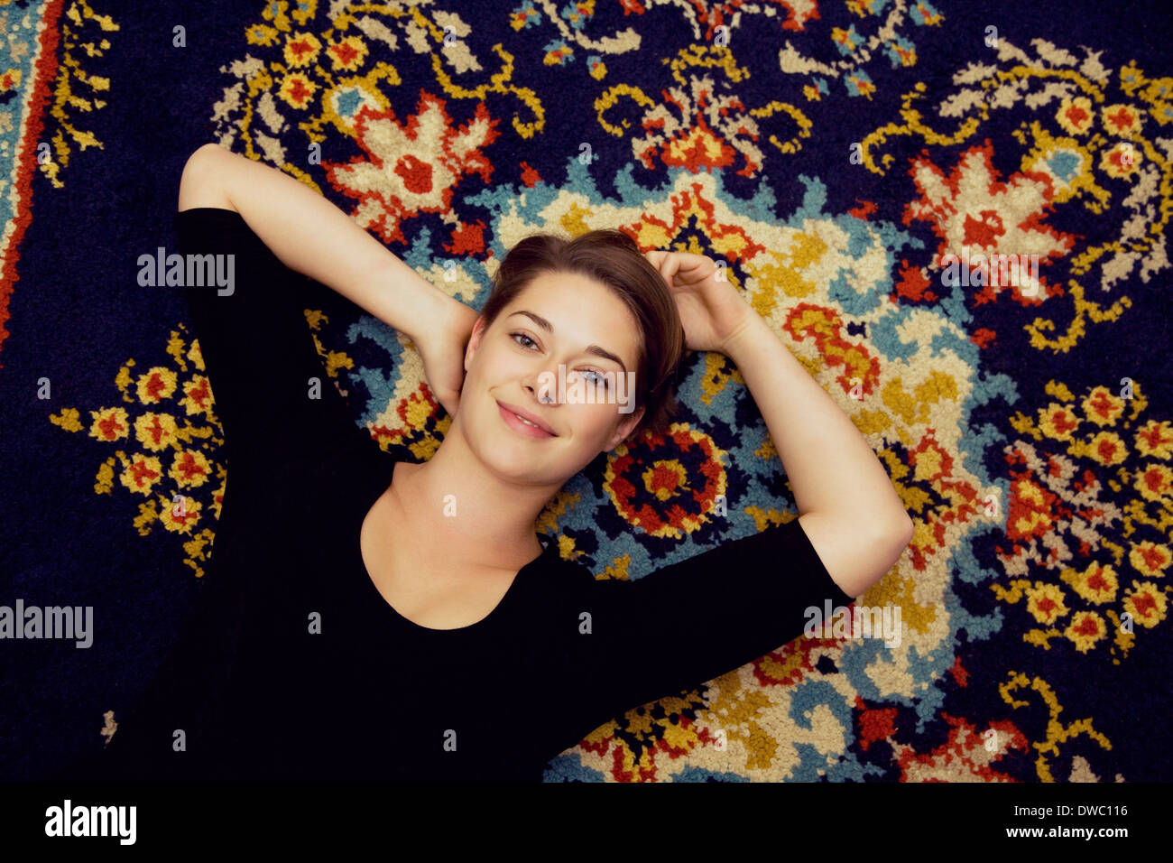 Portrait of young woman lying on tapis à motifs Banque D'Images