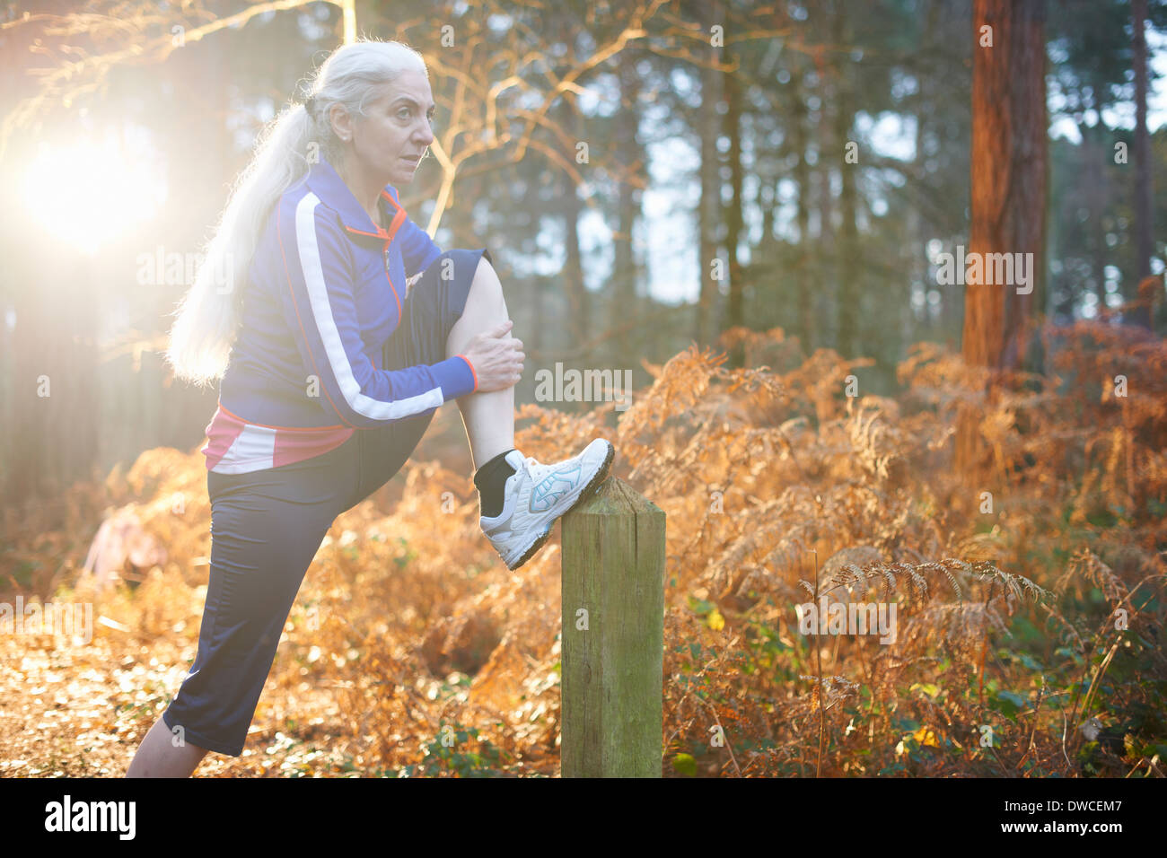 Mature Woman stretching leg sur wooden post Banque D'Images