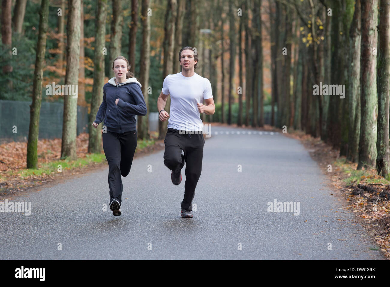 Couple running through forest Banque D'Images