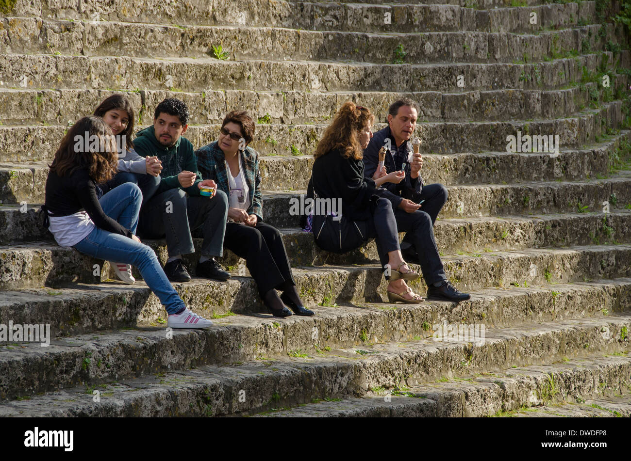 Groupe d'Italiens assis sur les étapes de la Piazza G. Garibaldi, dans le village perché de Massa Marittima, Italie. Banque D'Images