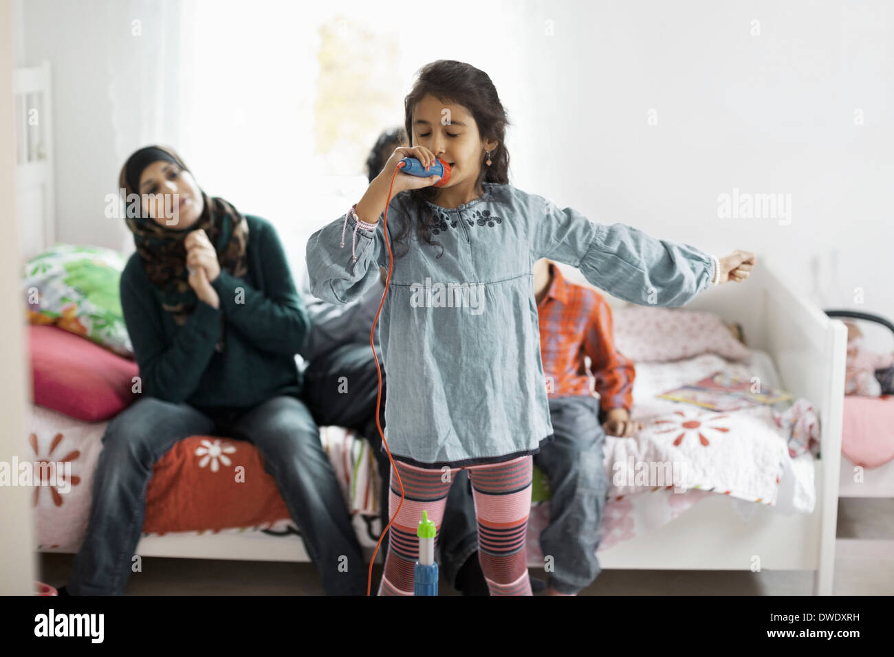L'écoute de la famille musulmane girl singing in bedroom Banque D'Images