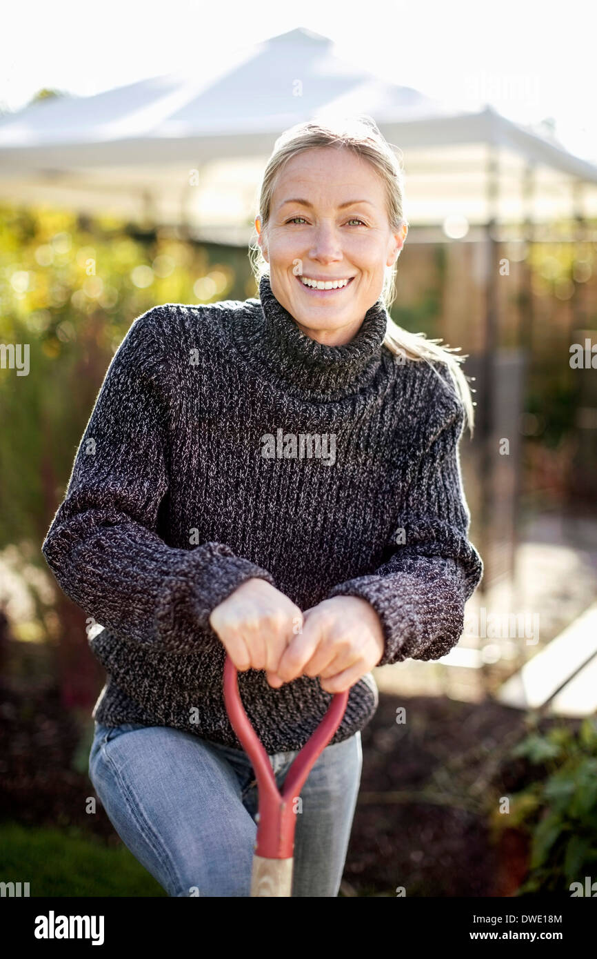 Portrait of smiling woman holding pelle à jardin Banque D'Images