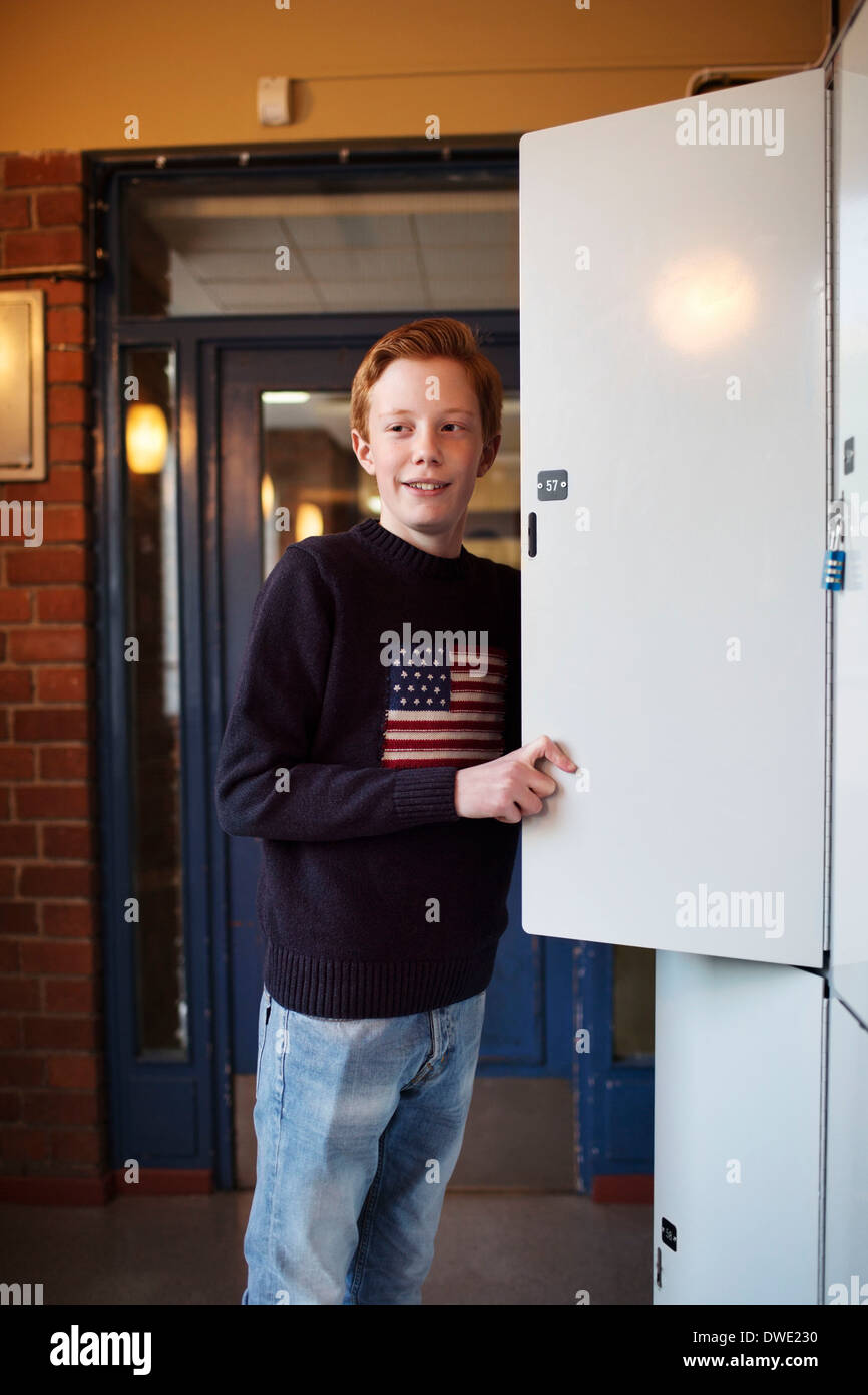 High school boy standing par locker Banque D'Images