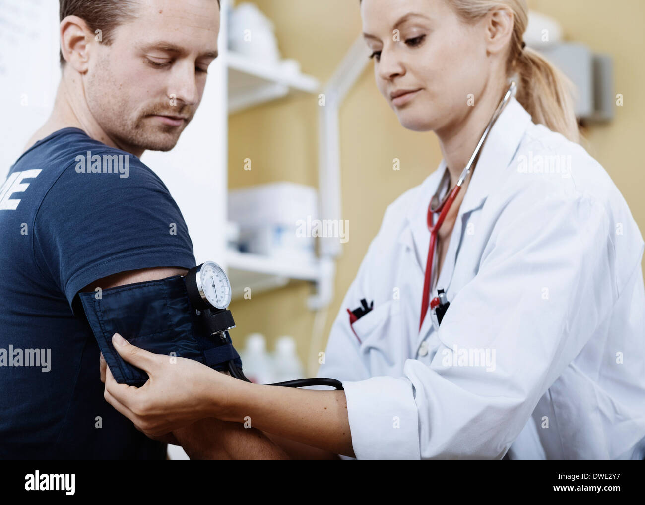 Femme médecin rétractable brassard au bras du patient avant de prendre la pression artérielle en clinique Banque D'Images