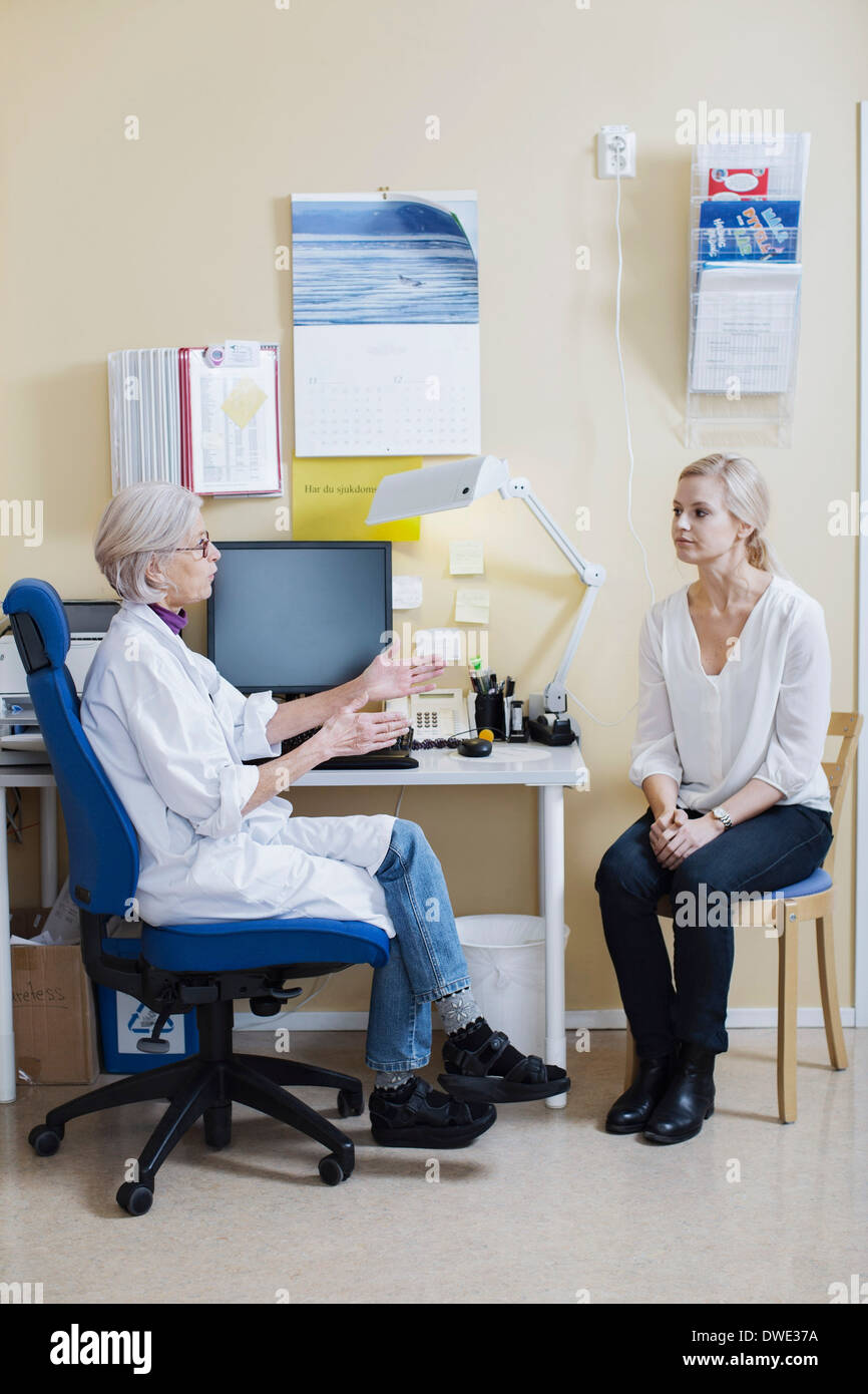 Toute la longueur de senior female doctor talking with woman in clinic Banque D'Images