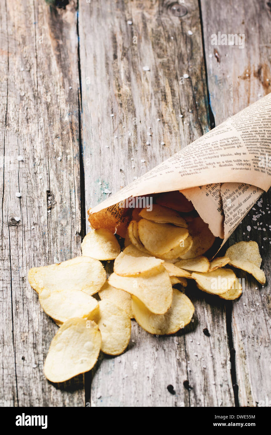 Cornet de papier avec les chips de pomme de terre avec du sel et poivre sur les tables en bois. Voir la série Banque D'Images