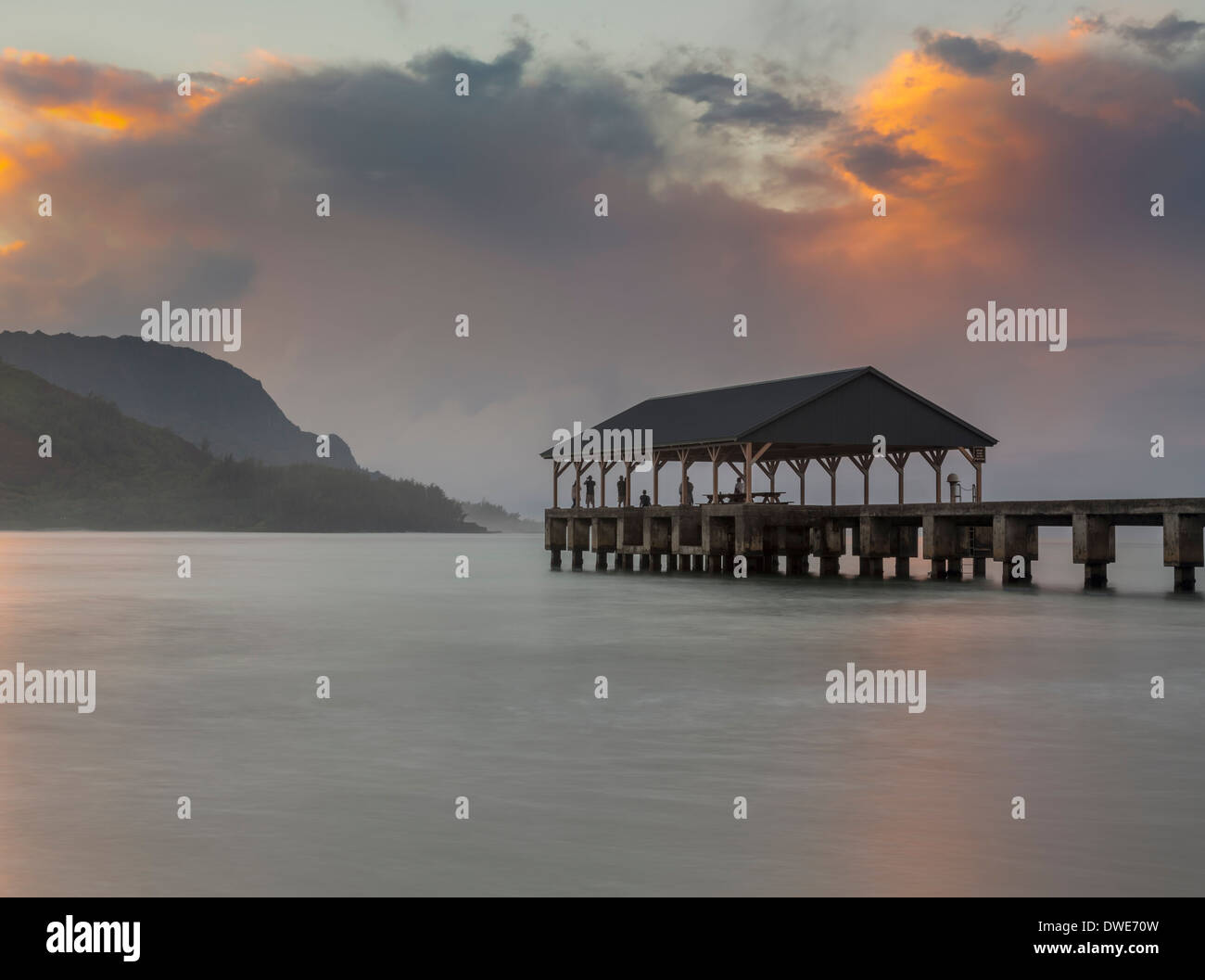 La baie de Hanalei, Kauai, Hawaii, USA - Les touristes sur le quai dans la mesure où le soleil illumine les sommets de montagnes de Na Pali Banque D'Images