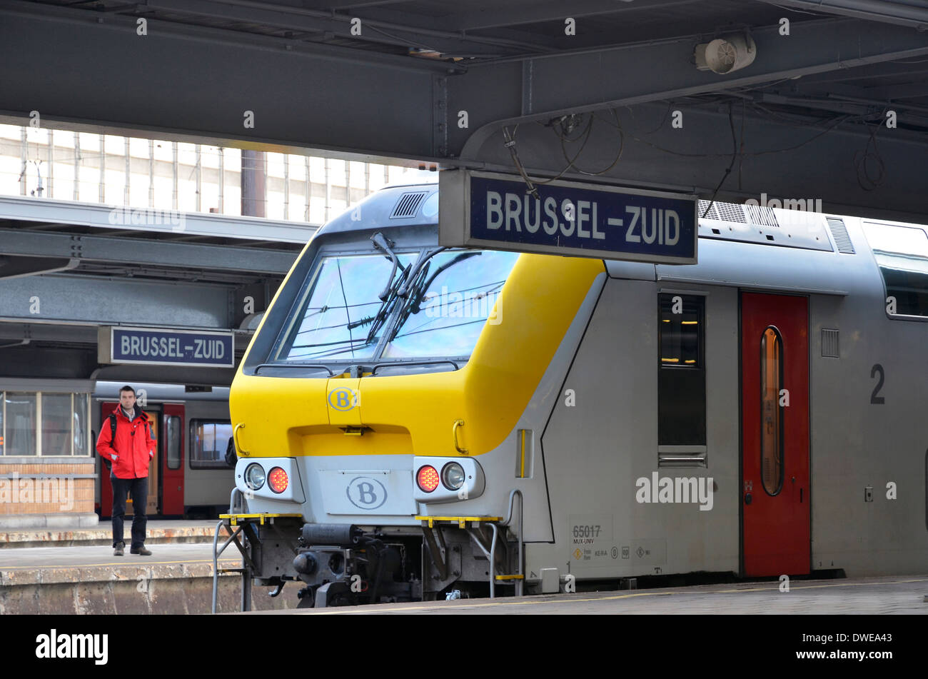 Train régional à Brussels-Zuid (permanent) withpassenger la gare Bruxelles-Midi en manteau rouge sur l'autre plate-forme. Banque D'Images