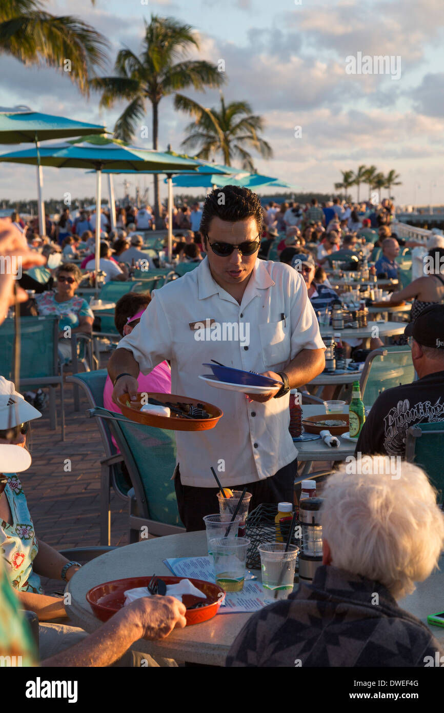 Key West, Floride - un garçon efface une table pour les touristes se sont réunis dans un restaurant de Mallory Square pour admirer le coucher du soleil. Banque D'Images