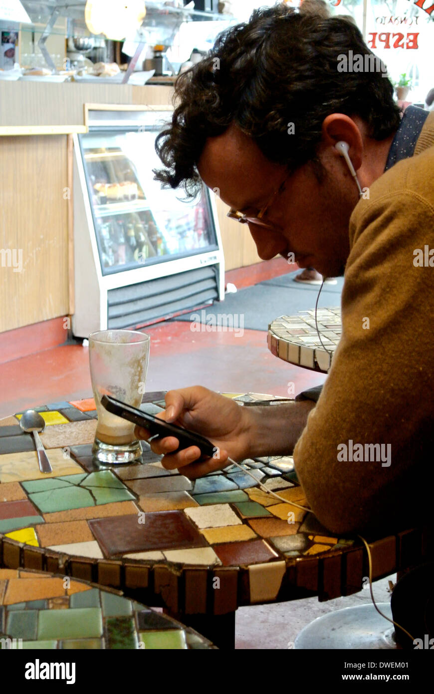 Man texting on cell phone in coffee shop à San Francisco Banque D'Images