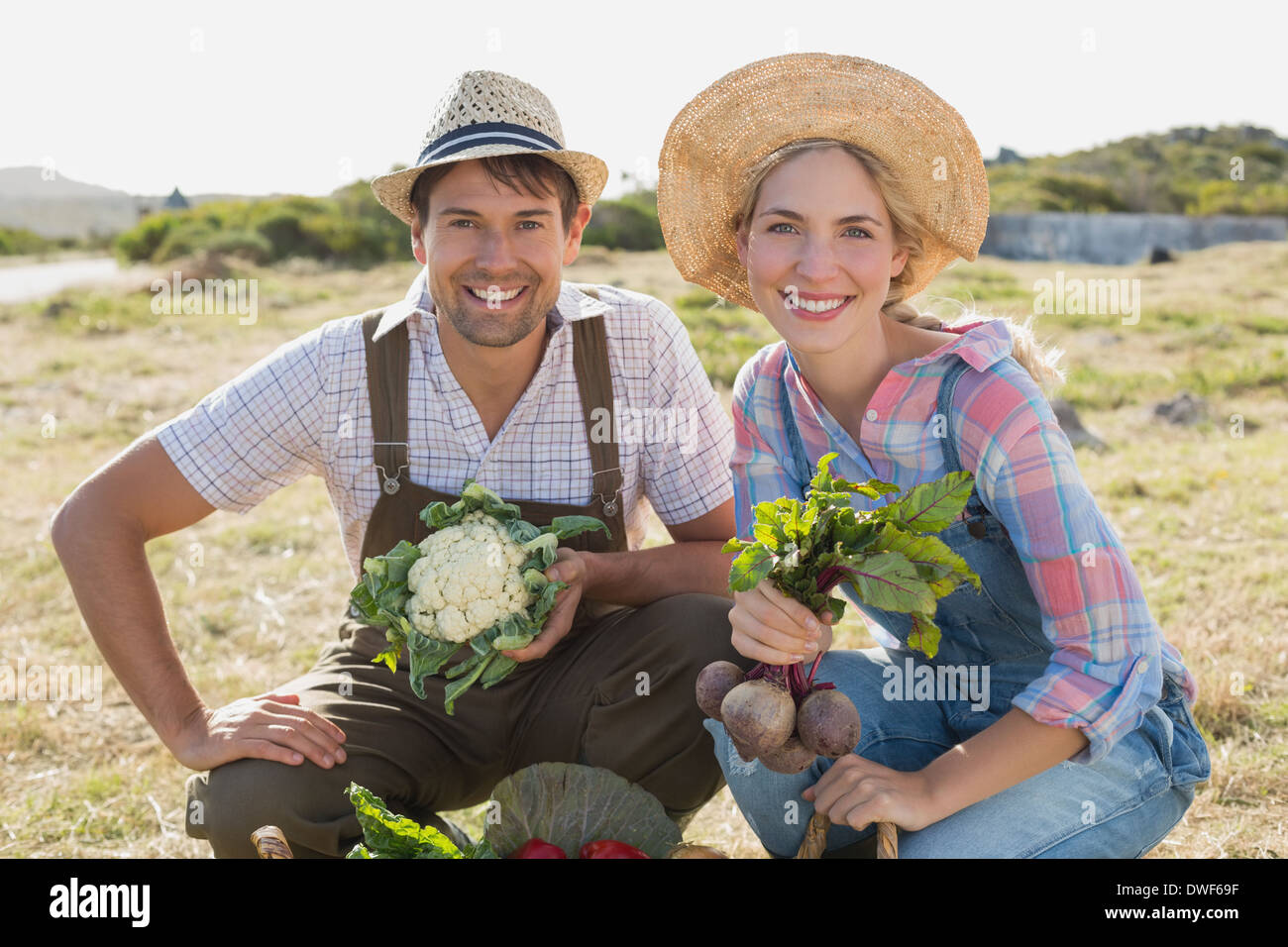 Smiling couple avec des légumes frais dans le champ Banque D'Images