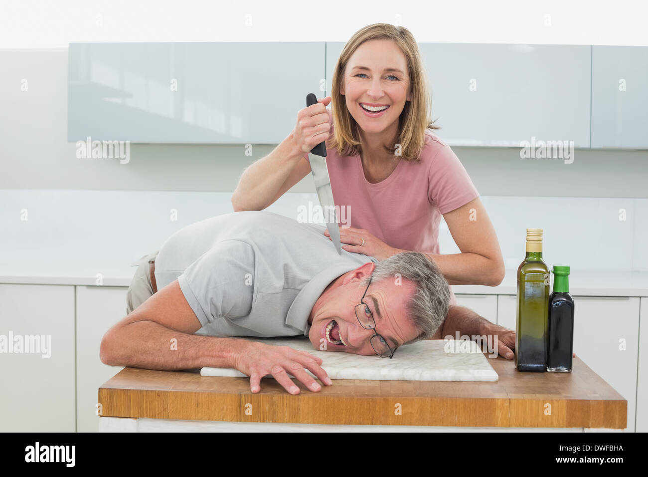 Happy woman holding couteau pour le cou de l'homme dans la cuisine Banque D'Images