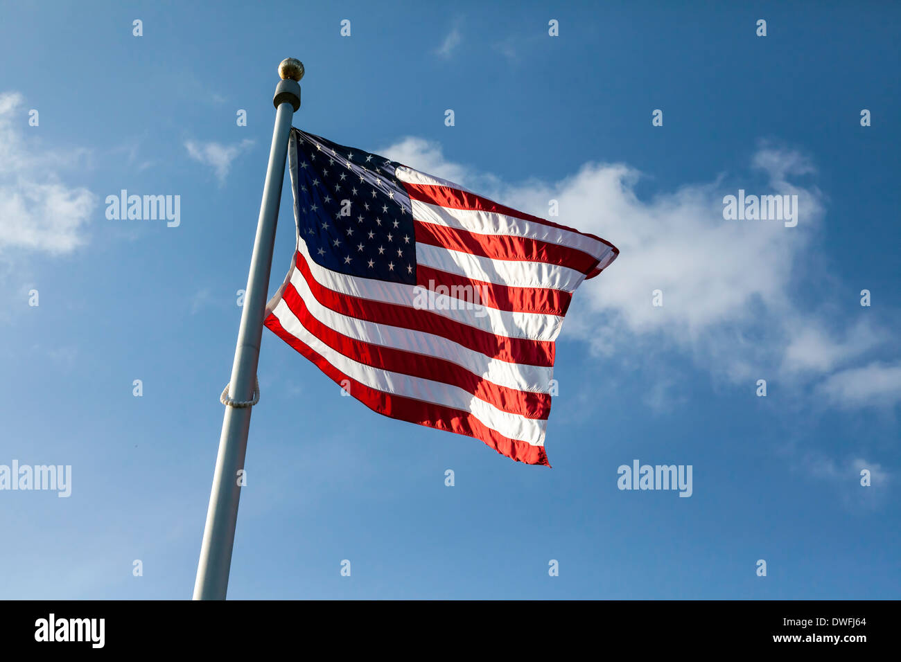 Drapeau américain également connu sous le nom de Old Glory ou Stars and Stripes vagues au sommet d'un mât contre un ciel bleu et nuages blancs. USA Banque D'Images