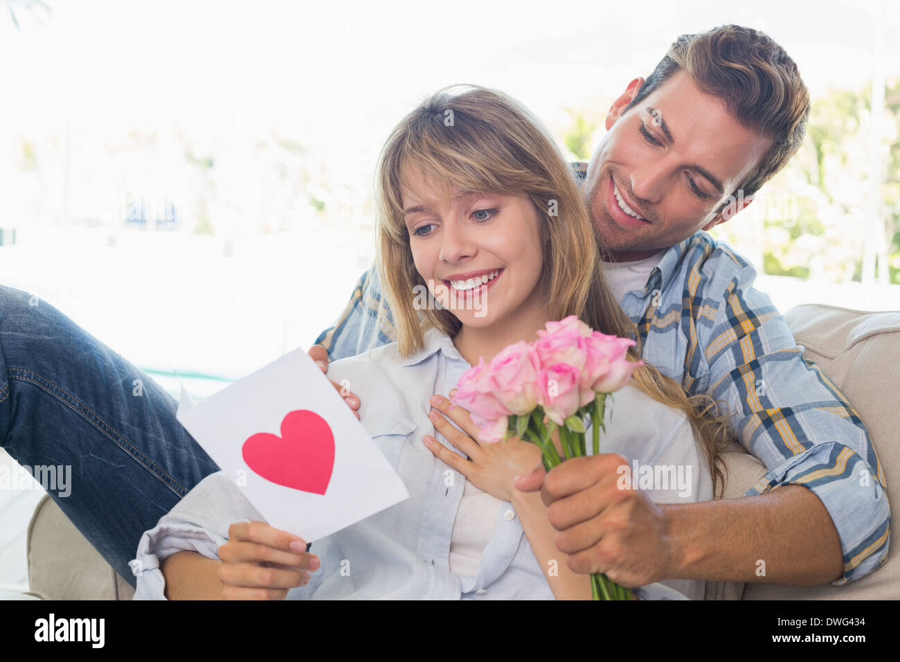 Couple avec fleurs et carte de souhaits à la maison Banque D'Images