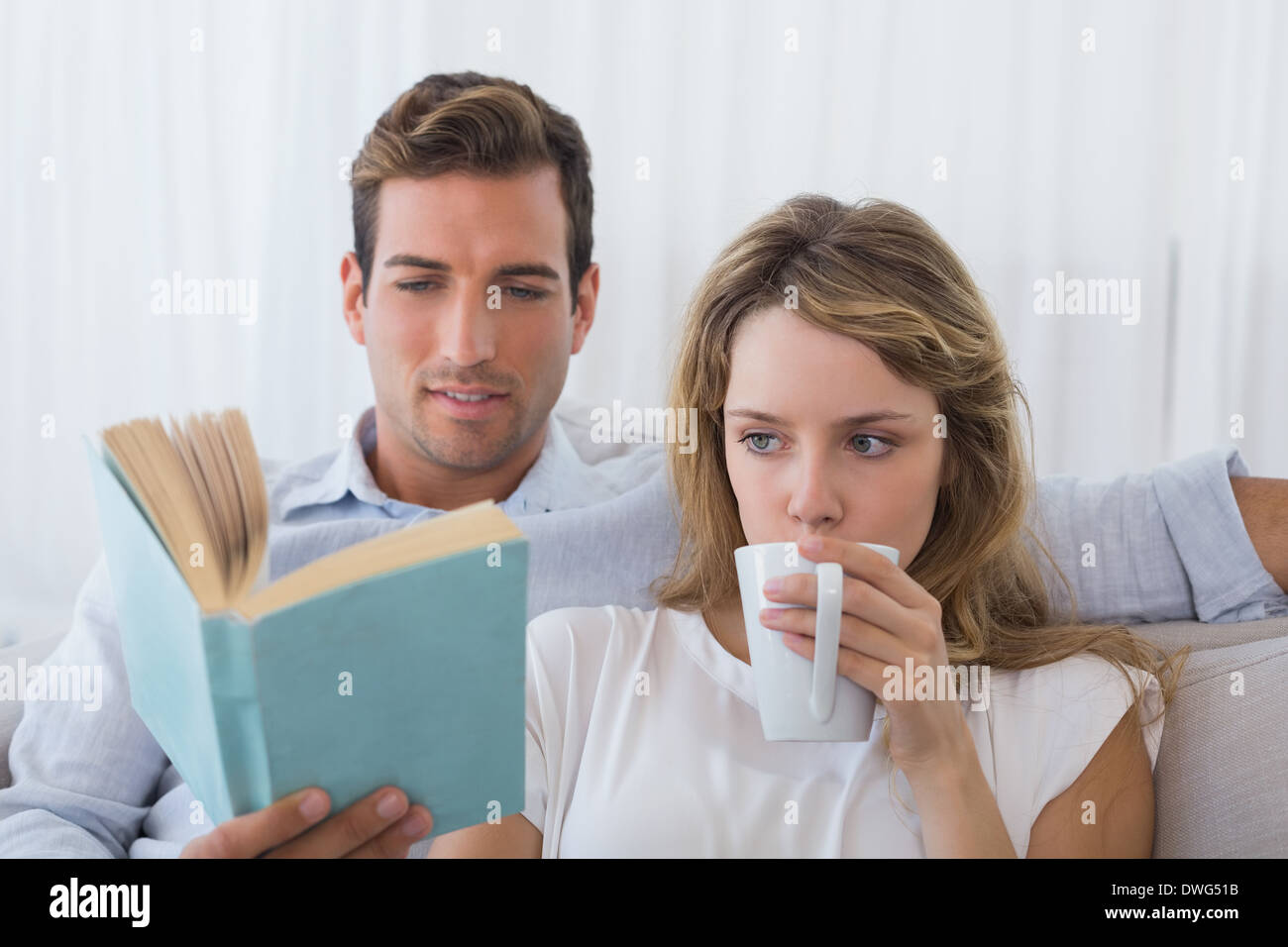 Couple reading book on couch Banque D'Images