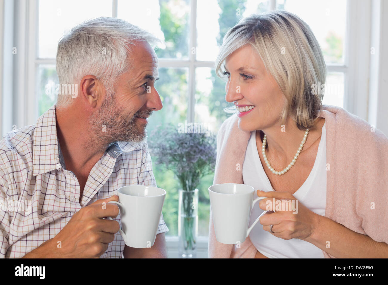 Smiling mature couple avec les tasses de café à la maison Banque D'Images