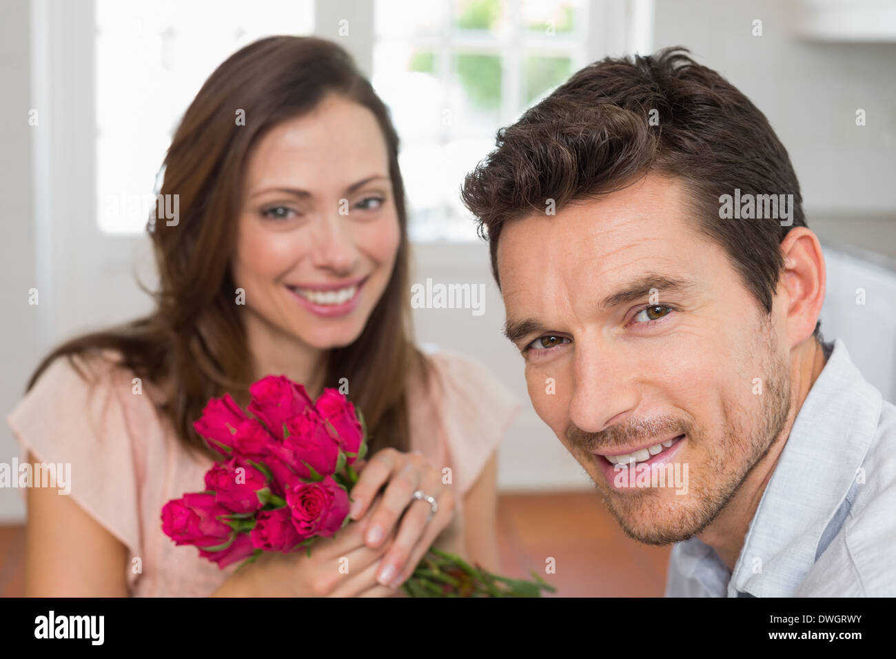 Jeune couple sympathique avec des fleurs à la maison Banque D'Images