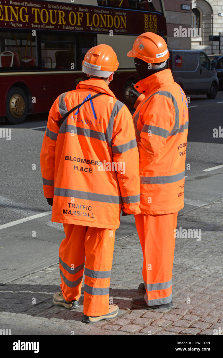 Deux marécages de circulation à haute visibilité en attente de superviser le déchargement de véhicules à l'extérieur du chantier de construction à Londres, Angleterre, Royaume-Uni Banque D'Images