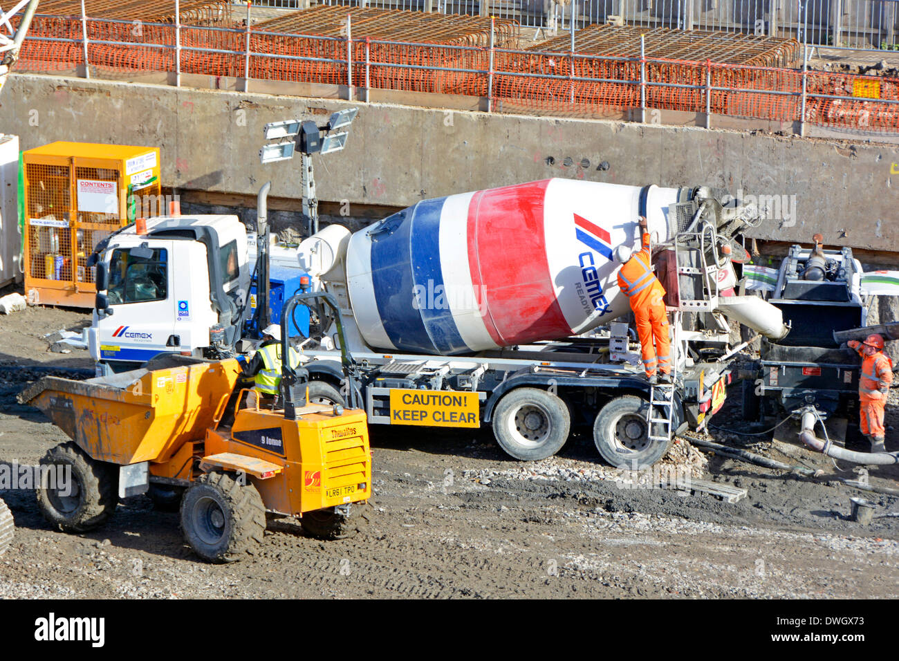 Tombereau et livraison de ciment en béton mélangé prêt à l'emploi vue du camion depuis le dessus les travailleurs portent des vêtements haute visibilité sur le chantier de construction Londres Royaume-Uni Banque D'Images