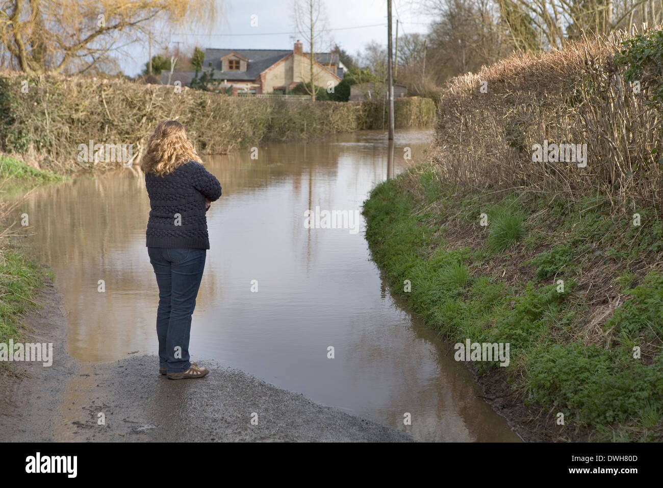 Une femme est debout avec les bras croisés au milieu de la route à la route inondée à la. Banque D'Images