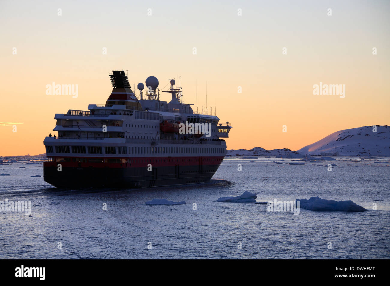 Soleil de minuit et un grand navire touristique dans le canal Lamairé dans l'Antarctique. Banque D'Images