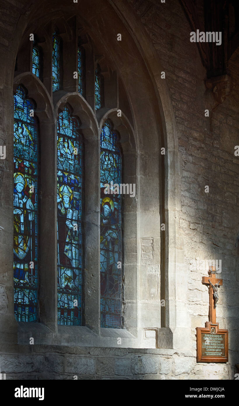 Vitraux et le Christ sur la croix à la lumière du soleil à St John the Baptist Church, Cotswolds, Burford, Oxfordshire, Angleterre Banque D'Images