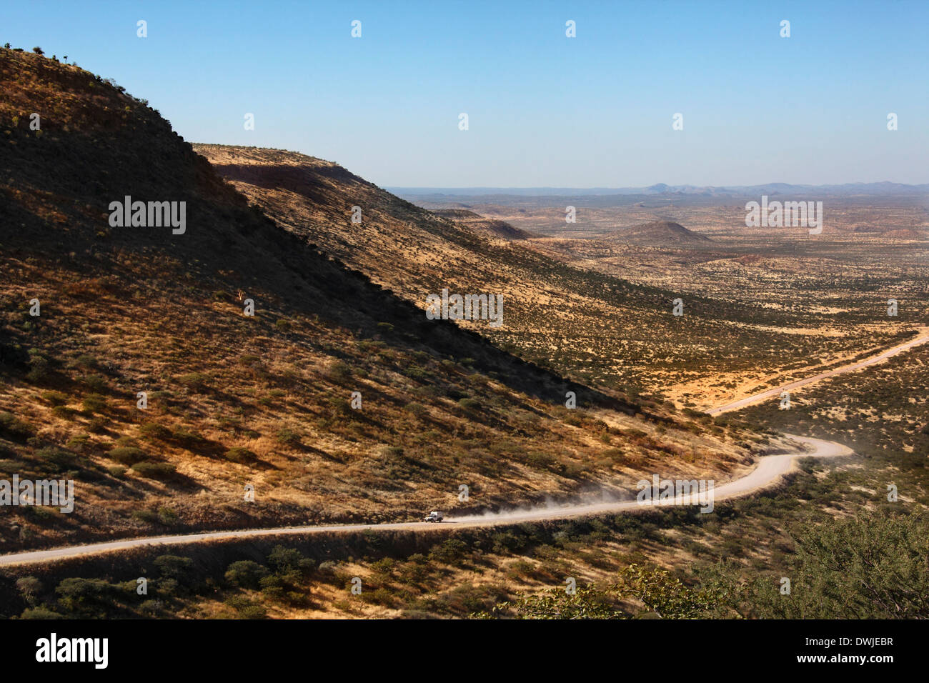 Véhicule sur une route à travers le désert à distance Pass Grootberg dans les zones semi-désertiques du Damaraland en Namibie. Banque D'Images