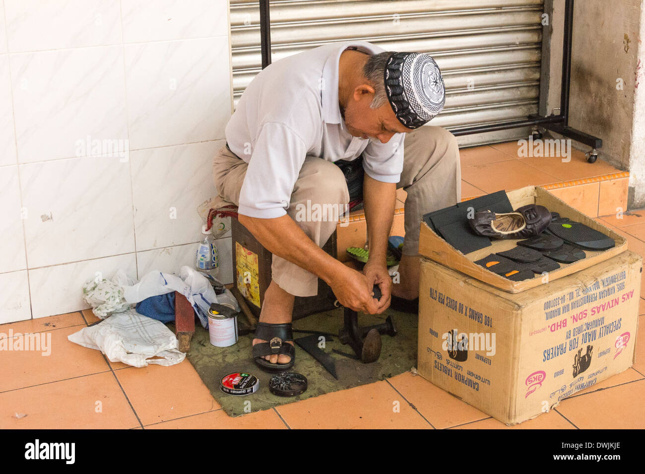 Un réparateur de chaussures au travail à Kuala Lumpar Banque D'Images