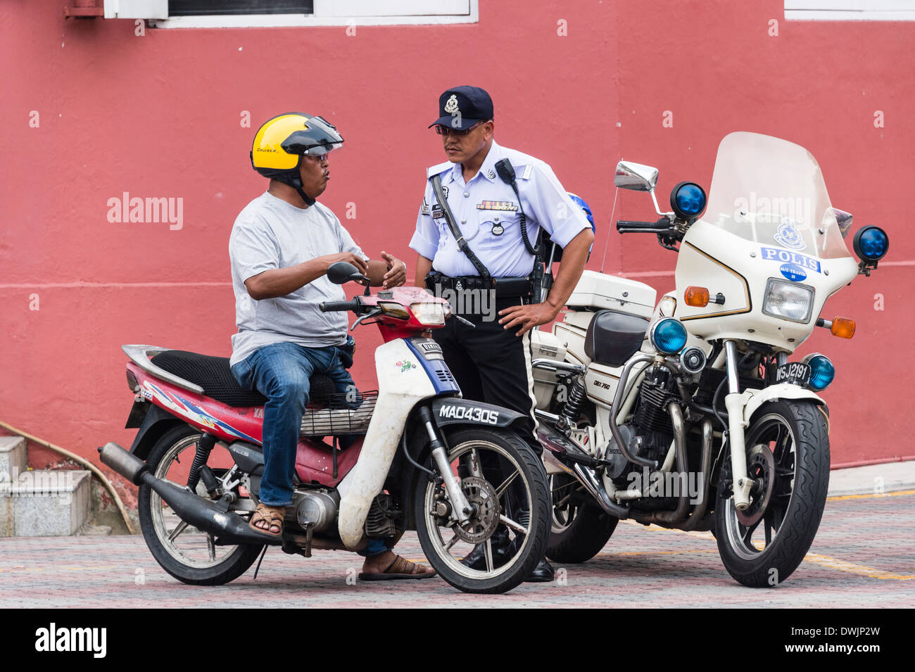 Un policier parle d'un moteur de cycliste à Malacca, Malaisie Banque D'Images