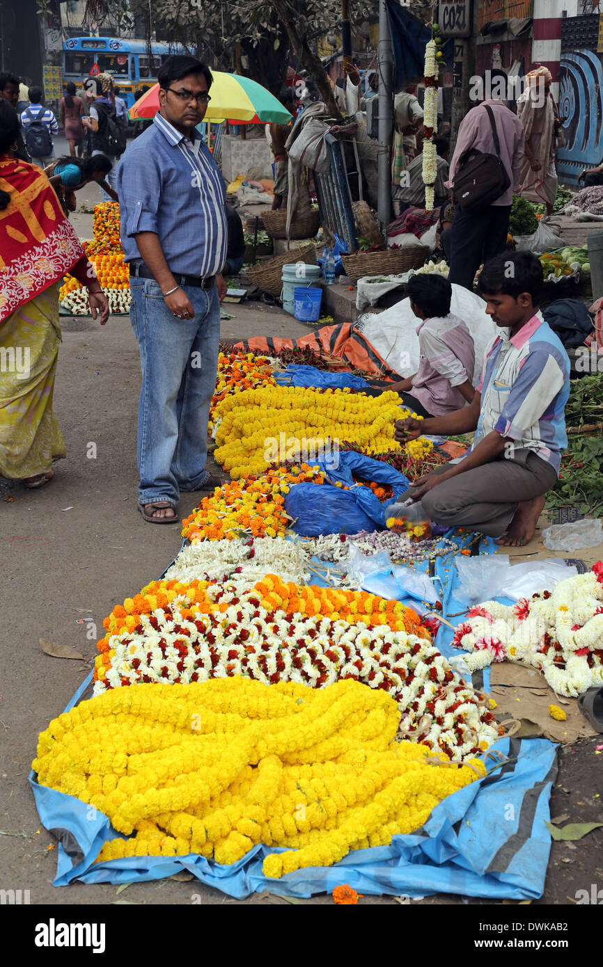 Les gens l'achat et la vente de fleurs et de guirlandes sur le marché aux fleurs à côté d'une voie de chemin de fer dans la région de Kolkata, Inde Banque D'Images