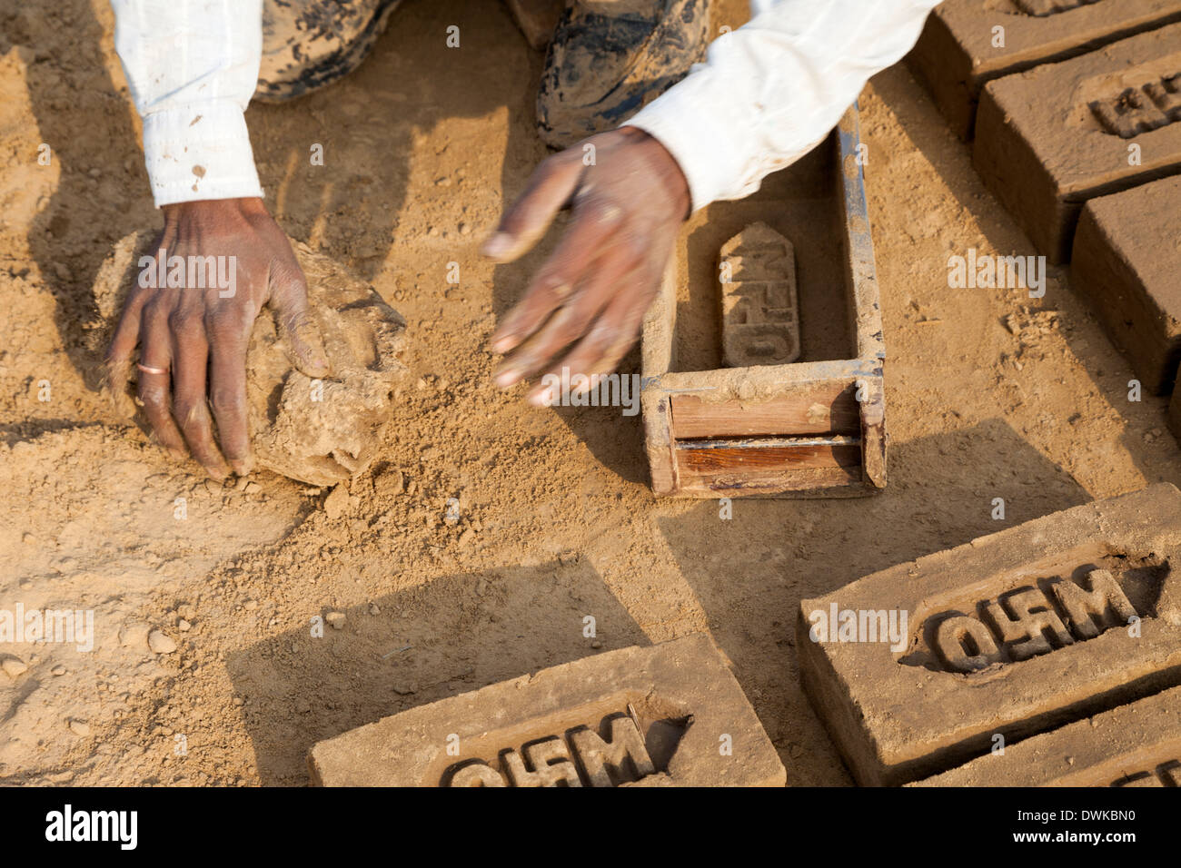 Le Rajasthan, Inde. L'homme la production de briques de boue formée par brique moule. Remarque la svastika hindou sur le logo de l'entreprise. Banque D'Images