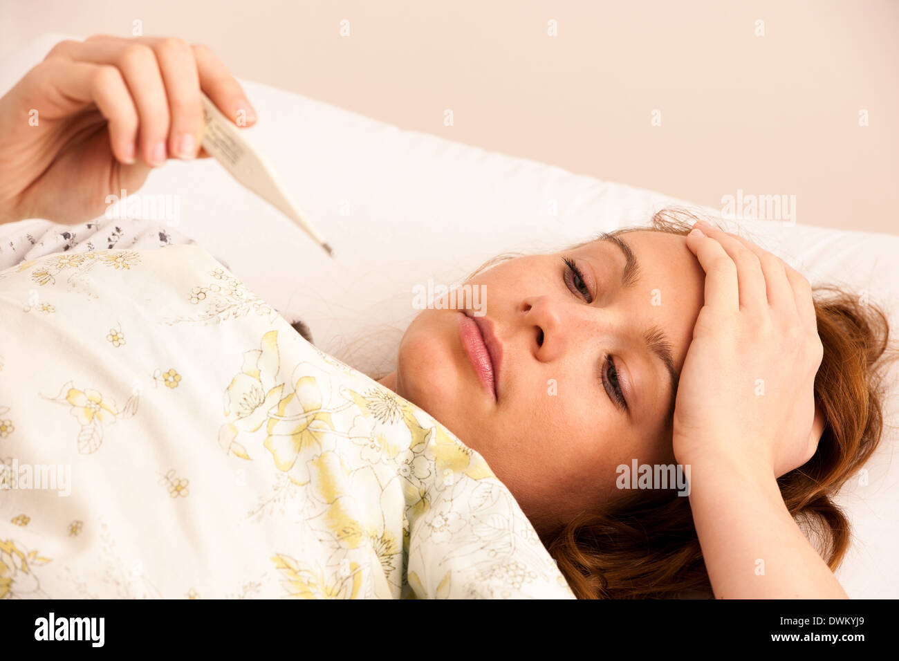 Woman with digital de la fièvre de la grippe a termomether avec girl resting in bed Banque D'Images