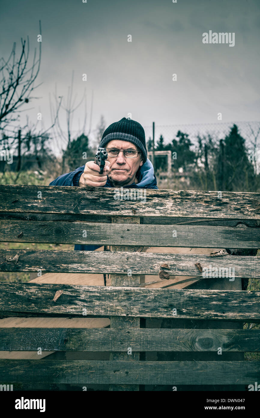 Man visant une arme sur vous et se cacher derrière barricade à l'extérieur. Banque D'Images