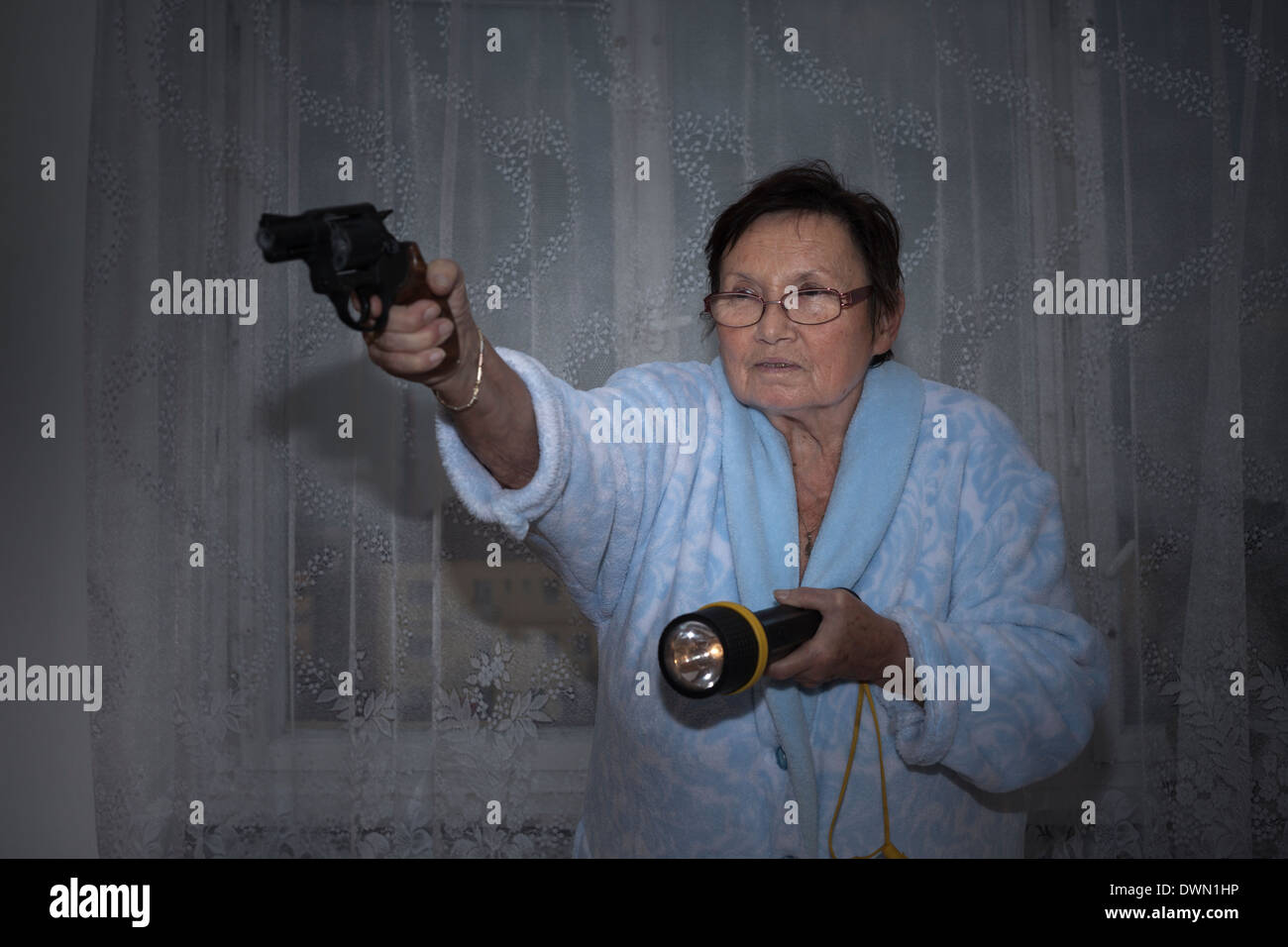 Peur senior woman visant une arme et lampe de poche. Banque D'Images