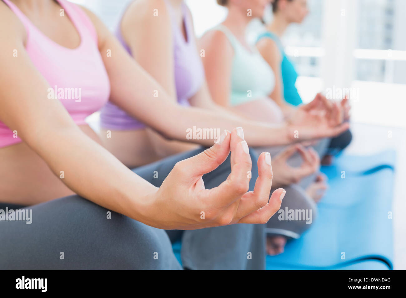 Les femmes enceintes pacifique méditant dans la classe de yoga Banque D'Images