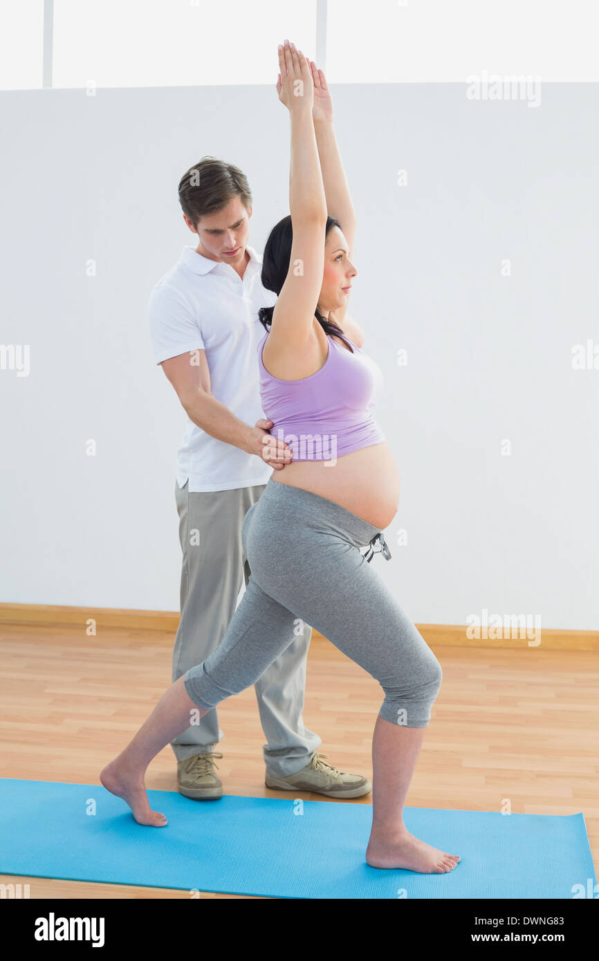 Pregnant woman doing yoga avec un entraîneur personnel Banque D'Images