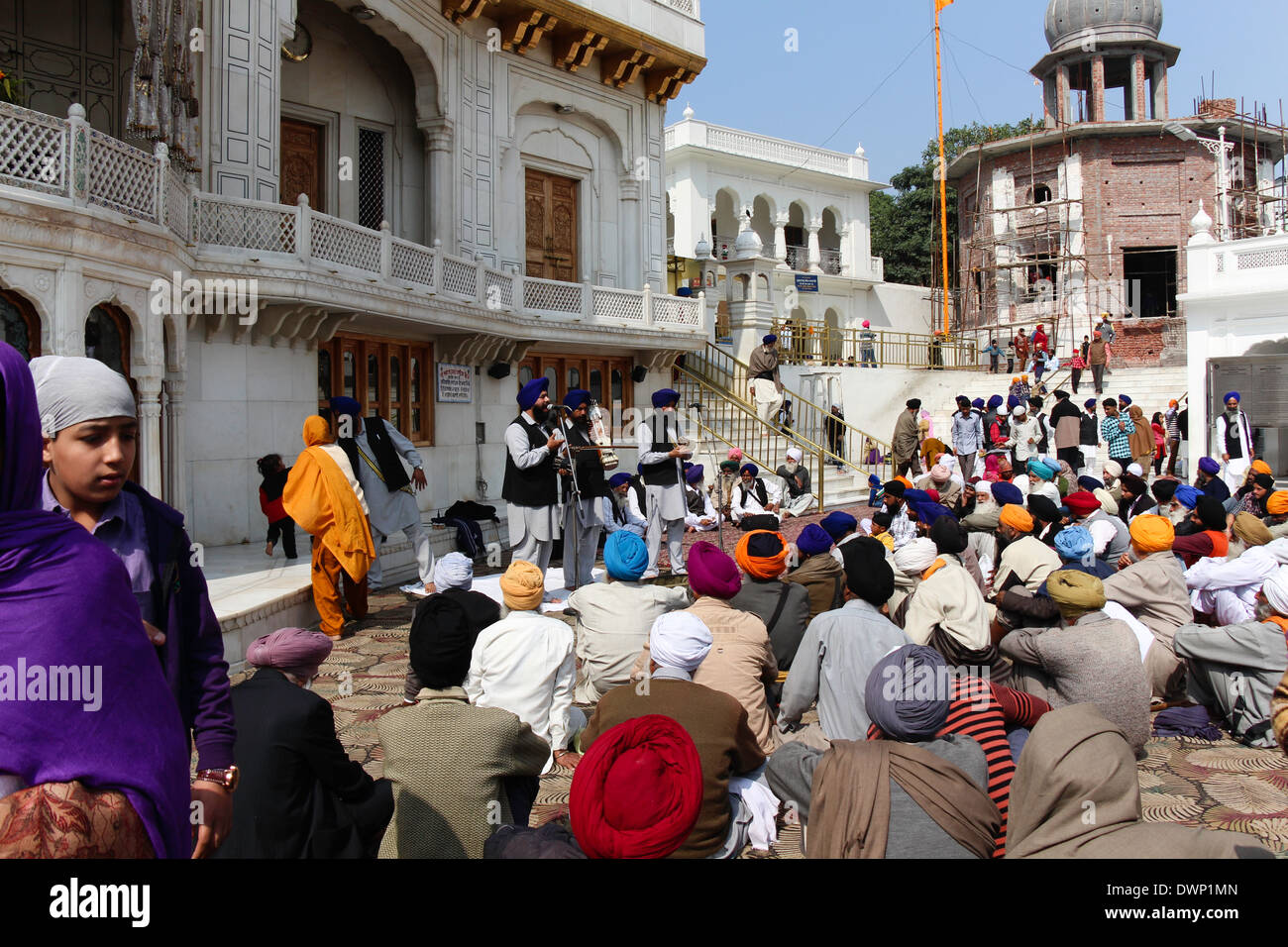 Les dévots à l'écoute de chants religieux en face de l'Akal Takht, assis sur le tapis et l'écoute d'un groupe de musique Banque D'Images